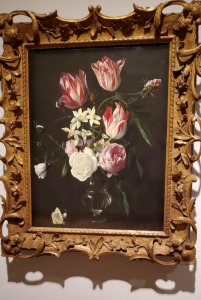 pink and white flowers on a black background surrounded by a intricately carved frame